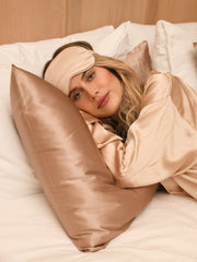 Woman lying on a silk pillowcase, wearing a silk sleep mask. The r and r collective. Luxury bedding.
