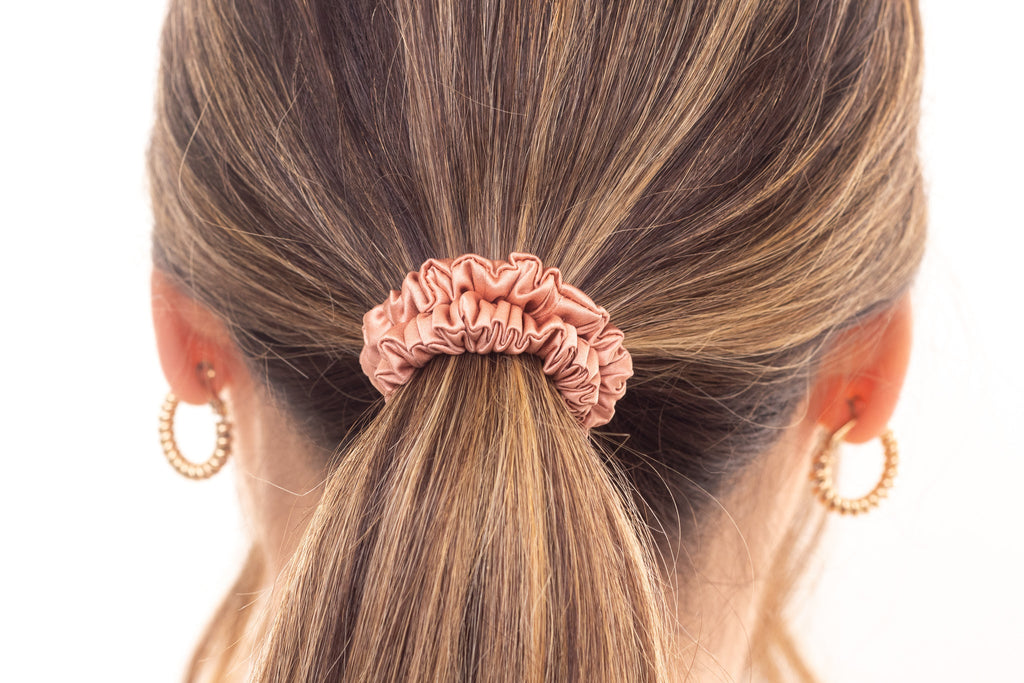 Rose gold silk hair scrunchie in woman's hair. The r and r collective.